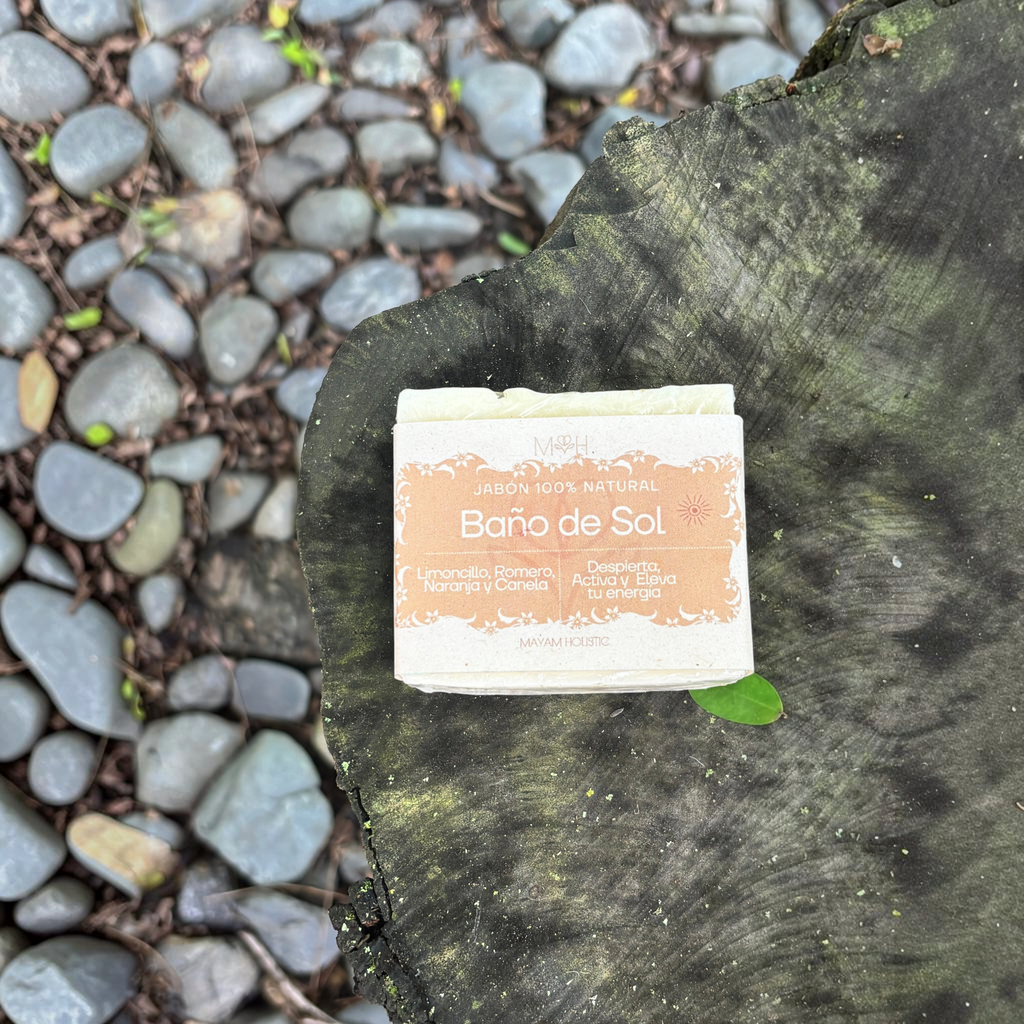 Jabón artesanal Mayam Holistic Baño de Sol con aceites esenciales sobre un tronco de madera en un entorno natural.