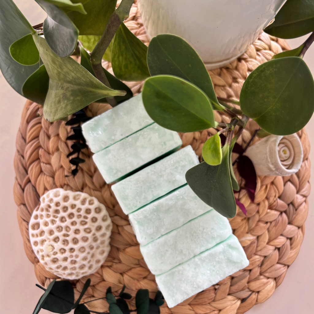 Jabón artesanal Mayam Holistic Baño de Mar de color verde claro sobre base de mimbre con decoración de coral y planta