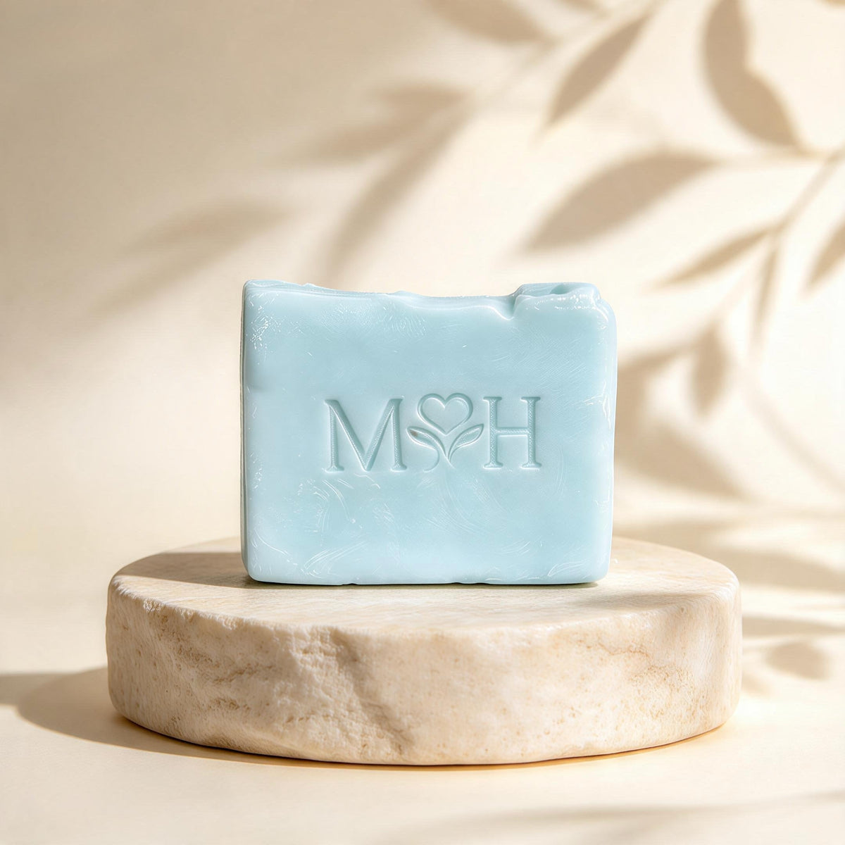 Jabón artesanal Mayam Holistic Baño de Mar color azul claro sobre base de piedra con relieve de logo y aroma herbal