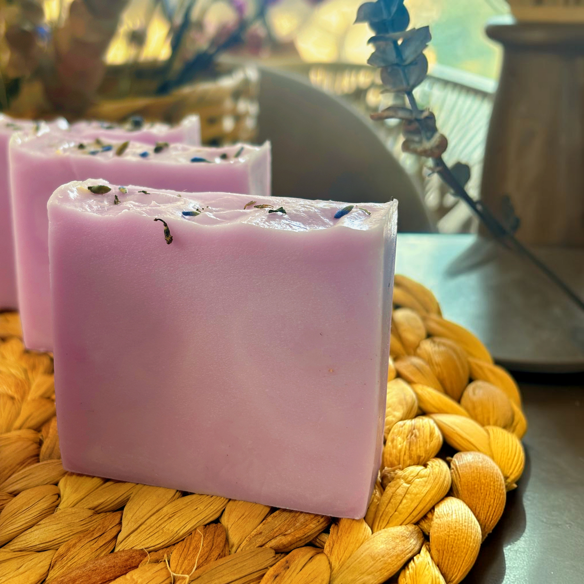 Jabón artesanal Mayam Holistic Baño de Luna color lavanda con flores secas sobre base de mimbre para relajación